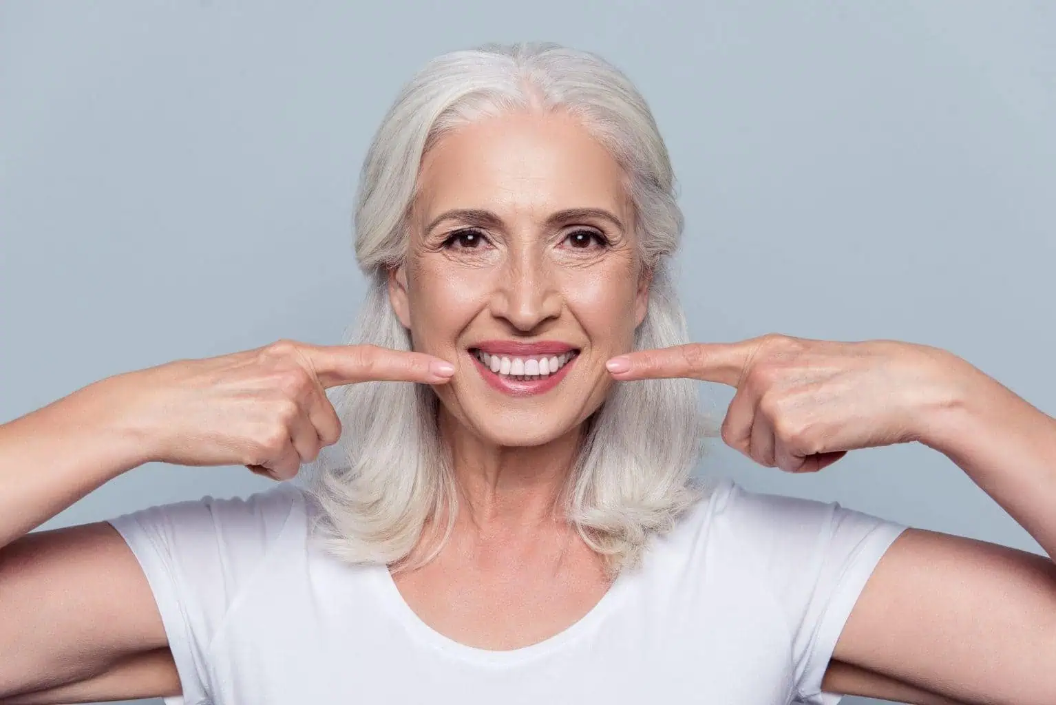 Smiling patient pointing to her new dental implant smile